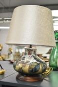 A Moorcroft pottery table lamp of baluster form, decorated with foliage and floral patterns,