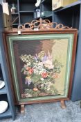 A vintage hardwood fire guard with a cross stitch panel containing a Margot de Paris floral still