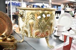 A brass log basket of circular form having embossed decoration and raised on paw feet, h34cm