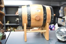 A coopered oak spirit barrel with black painted coopers, wooden spiggot and stand 34.5cm overall.