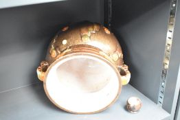 A brown glazed pottery vase decorated with geometrical patterns, two handles and raised on ball