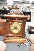An early 20th century mahogany and pine wood cased mantel clock, the finial topped surmount over a