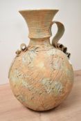 A 20th century terracotta vessel, having textured body, trumpet spout and ripple style handle,