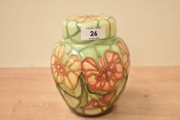 A Moorcroft pottery ginger jar with cover, decorated with floral patterns on a green ground, painted