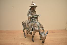 A Japanese 'toyo' cast metal figure of a gentleman on horse back, roughly cast with gilt paint and