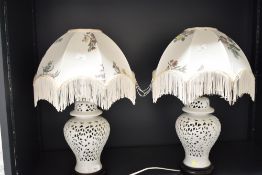 A pair of table lamps of baluster form, having floral shade and pierced decoration, raised on a