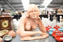 An attractive terracotta sculpture of a nude female figure, crouching with her left hand resting