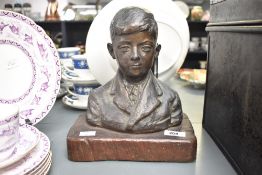 A metal bust of a boy raised upon a wooden base, signed to back 'Michael AB 1938', H24.5cm