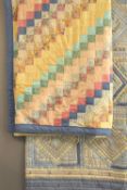 Two 20th century vintage heavyweight patchwork quilts featuring cool toned floral and plaid fabrics.