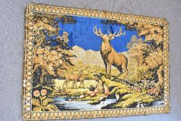 A vintage wall hanging or area rug in woven velvet, depicting a stag and deer in a wooded glade with