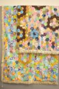 Two mid-century hexagonal patchwork quilts showcasing an array of brightly coloured floral and