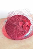 Three ladies fascinators or wedding hat / headpieces, each with a net veil, in red, burgundy and