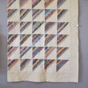 A large patchwork quilt in cream cotton-linen, having floral stitching border and central grid