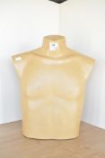 A mid-century shop mannequin of the male torso in thick camel coloured moulded plastic, has