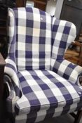 A traditional wingback armchair having blue and white check upholstery