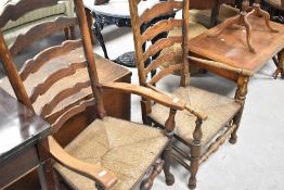 Two traditional oak ladder back carver chairs having rush seats