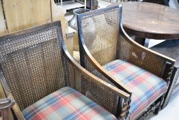 A pair of early 20th Century oak armchairs having canework panels and barley twist supports, with