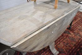 A limed oak drop leaf dining table, having solid turned support and quadruple splay legs