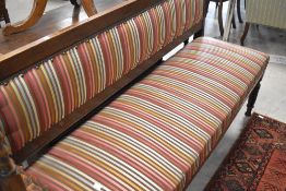 A Victorian oak framed waiting room style settee having later multi coloured stripe upholstery,