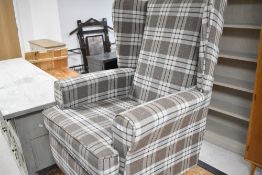 A modern wing back easy chair having brown check upholstery