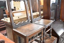 A pair of small proportioned period oak hall chairs having open backs, solid seats and turned