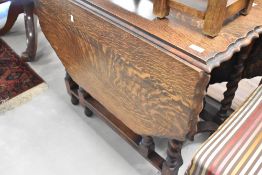 An early 20th Century oak gateleg dining table having shaped top and twist frame, width approx.