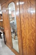 A Victorian walnut triple wardrobe, having central mirror door, height approx. 213cm, width 196cm