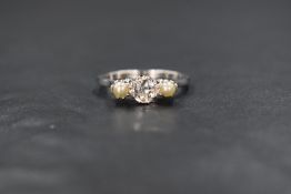An 18ct white gold pearl and diamond set trilogy ring, the central old cut diamond measuring