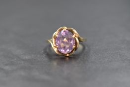 A yellow metal amethyst ring stamped 9ct, the oval amethyst being in a claw set frilled mount on a