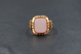 A yellow metal signet ring having central chalcedony panel in a triple claw set collared mount to an