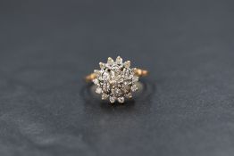 A yellow metal presumed gold diamond set cluster ring, the central diamond with a six diamond