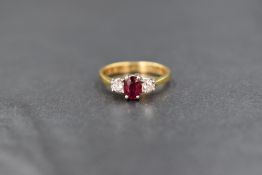 An 18ct gold ruby and diamond ring, the central oval ruby, approx 0.25ct flanked by two diamonds,