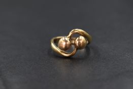 A 9ct gold cross over ring, the gold balls in a cross over setting, marked 375, ring size L-M, 5.2g