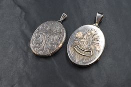 Two large silver lockets, both having scroll decoration with one having a floral design with '