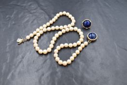 A string of cultured pearls of even form having a yellow metal circular lapis lazuli mounted box