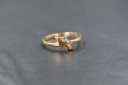 A 9ct gold emerald set ring, the round cut emerald measuring approximately 0.04ct, in a geometric