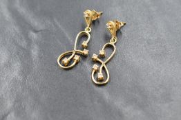 A pair of yellow metal earrings for pierced ears having a cubic zircona set stud with looped