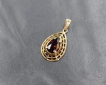 A 9ct gold garnet set pendant, the pear cut garnet in a four claw setting within a pierced pear