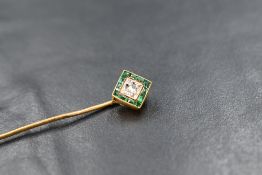 A French 18ct gold stick pin having a diamond and emerald set terminal, damage to one emerald,