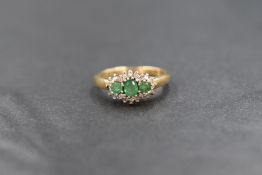 A 9ct gold emerald and diamond ring, the central trio of small emeralds within a border of diamond