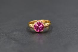 A 22ct gold pink sapphire set solitaire ring, the later addition rose gold bezel set round cut