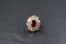 An 18ct gold ruby and diamond set cluster ring, the central oval cut ruby measuring approximately