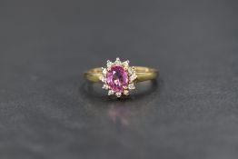 A 9ct gold pink sapphire and clear gemstone set cluster ring, the central oval cut sapphire