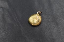 A gold nugget pendant, having two pendant loops marked 9ct with a horseshoe to the reverse, 2cm