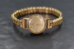 A 9ct gold cased vintage Omega wristwatch, the champagne dial having baton numerals, on a rolled