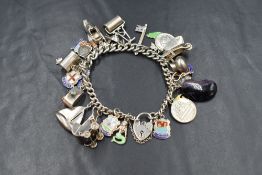 A silver charm bracelet, the curb link bracelet having a silver heart padlock and twenty-six