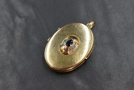 A 9ct gold sapphire and diamond set locket, the central bezel set oval sapphire with illusion set