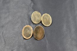 A pair of 9ct gold cufflinks, the oval panels with one side having an engraved scroll border with