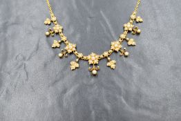 A yellow metal presumed gold seed pearl set floral fringe necklace, having pearl set alternating