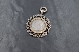 A Victorian one shilling coin, in a white metal decorative mount, 11.4g